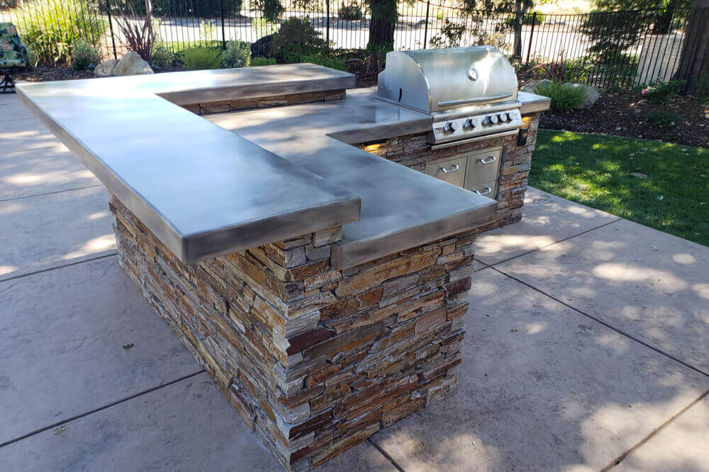 U-shaped outdoor kitchen with ledgestone base and granite counters