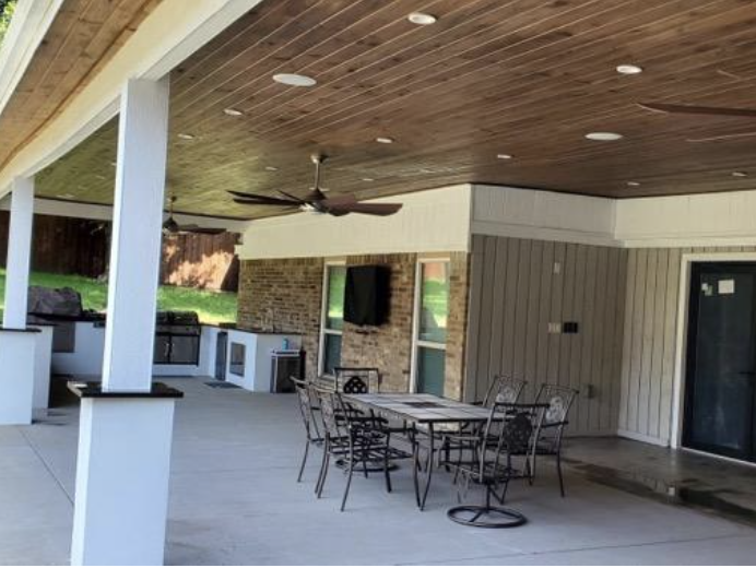 Large covered patio with wood ceiling, fans and dining area