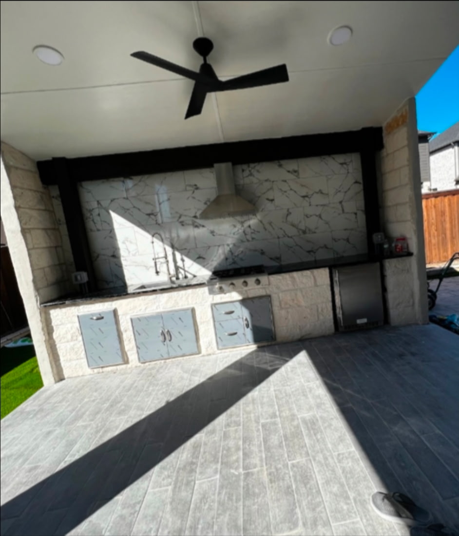 Modern outdoor kitchen with marble backsplash and vent hood