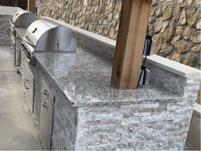 Long linear outdoor kitchen island with dual grills and stacked stone base
