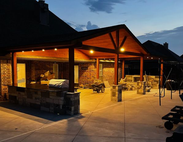 Outdoor kitchen pavilion lit at dusk during construction