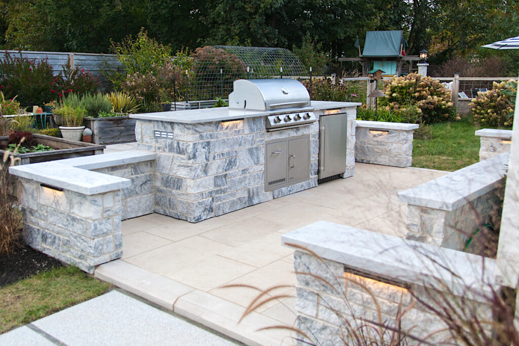 Courtyard-style outdoor kitchen with stone benches and LED lighting