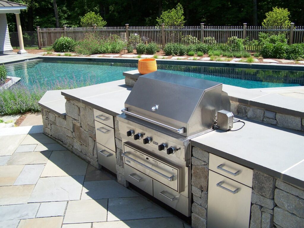 Poolside outdoor kitchen with fieldstone island and Viking grill
